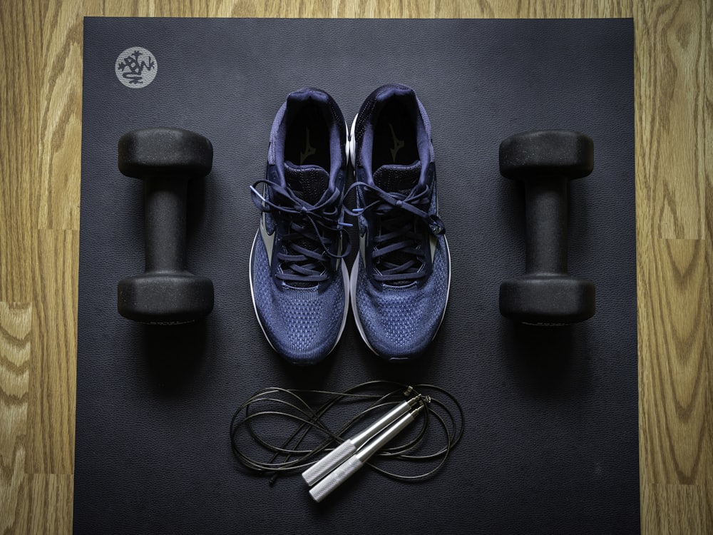 Hanteln, Sportschuhe und Springseil auf einer Trainingsmatte